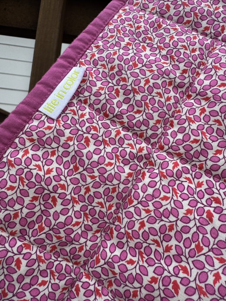 Handmade quilt with pink leaf print and 'Life in Color' tag
