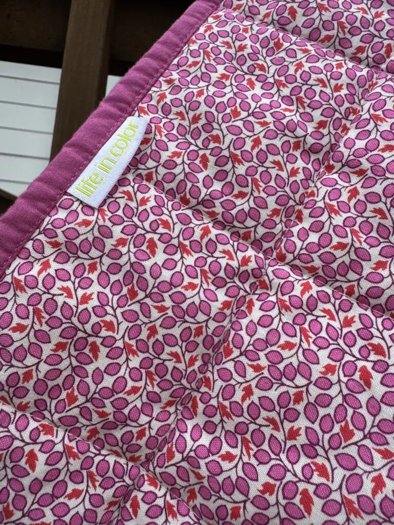 Handmade quilt with pink leaf print and 'Life in Color' tag
