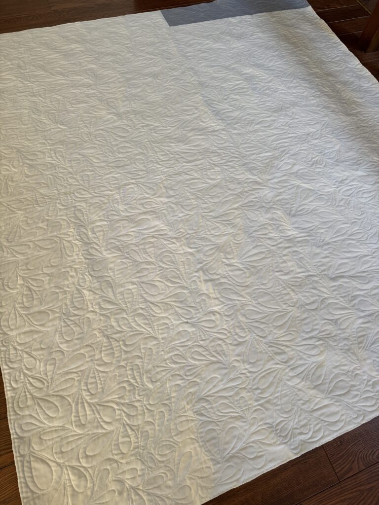 White quilt with cross on point blocks and feather quilting