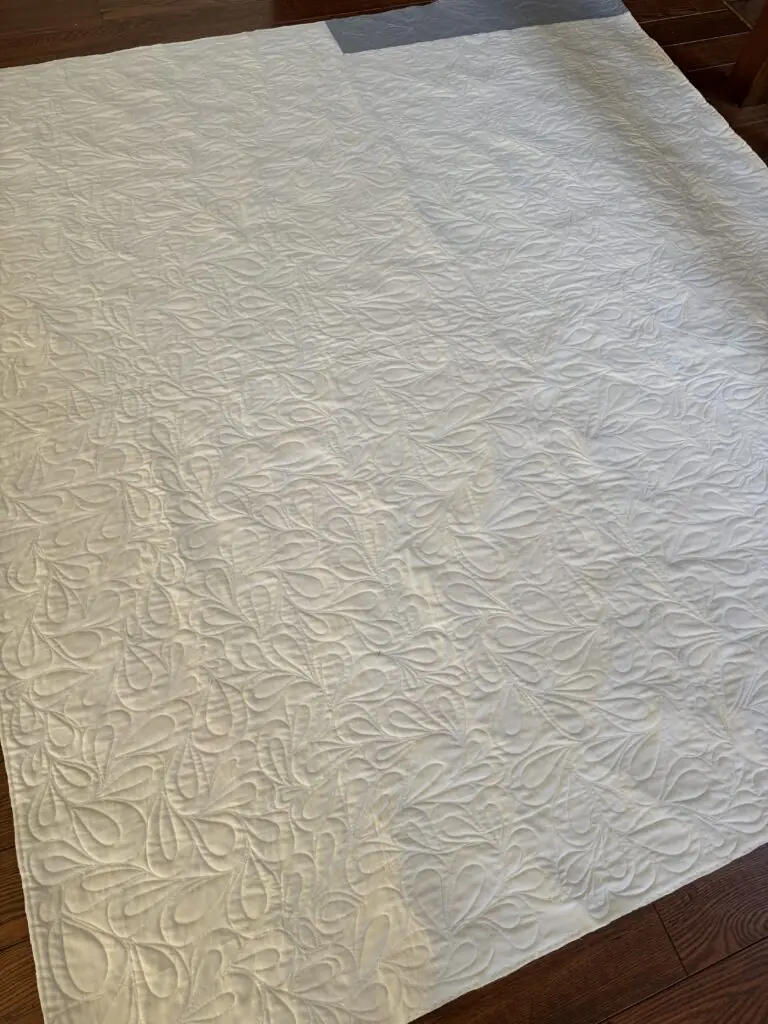 White quilt with cross on point blocks and feather quilting